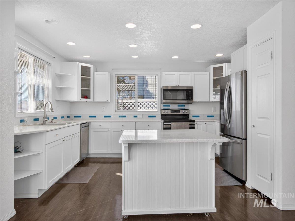 398 Pebble Beach Way Eagle, ID 83616 - Photo 9 of 35 Kitchen featuring white cabinetry, wood-finish flooring, recessed lighting, stainless steel appliances, and a central island
