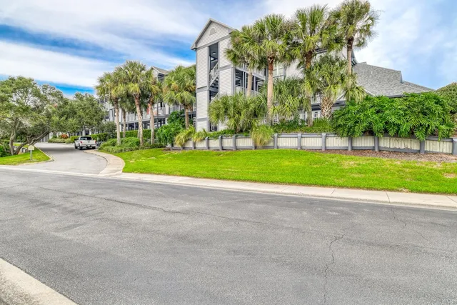 a view of a house with a big yard and palm trees