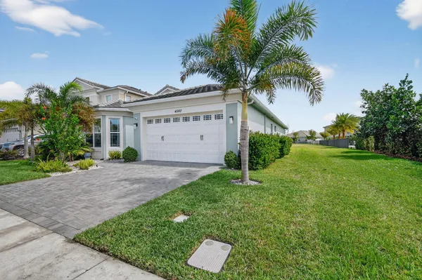 a view of a white house with a yard and palm trees