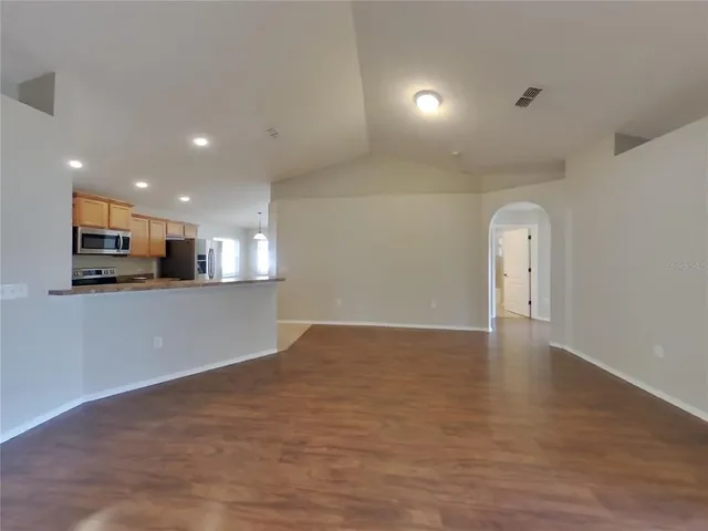 a view of a kitchen with a sink and dishwasher a stove top oven with wooden floor