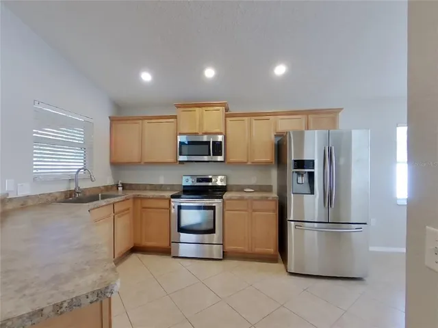 a kitchen with stainless steel appliances granite countertop a refrigerator a stove a sink and a refrigerator