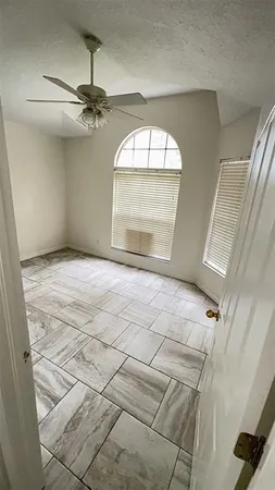 an empty room with windows and fan