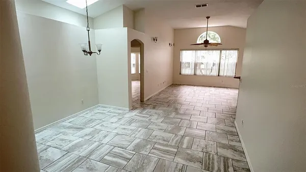 a view of an empty room and chandelier fan