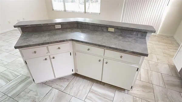 a kitchen with white cabinets and a window