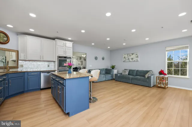 a large living room with stainless steel appliances granite countertop a couch and a wooden floors