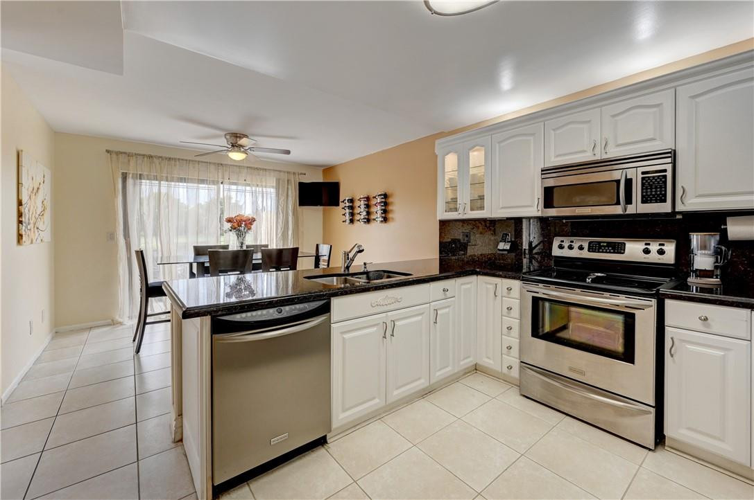8129 Boca Rio Drive Boca Raton, FL 33433 - Photo 11 of 39 a kitchen with stainless steel appliances granite countertop a sink and cabinets
