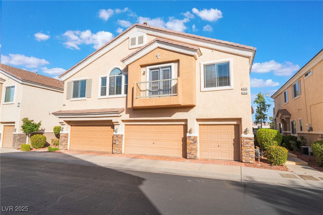 1570 Rusty Ridge Lane Henderson, NV 89002 - Photo 1 of 35 View of front of house with cooling unit, stucco siding, stone siding, an attached garage, and driveway