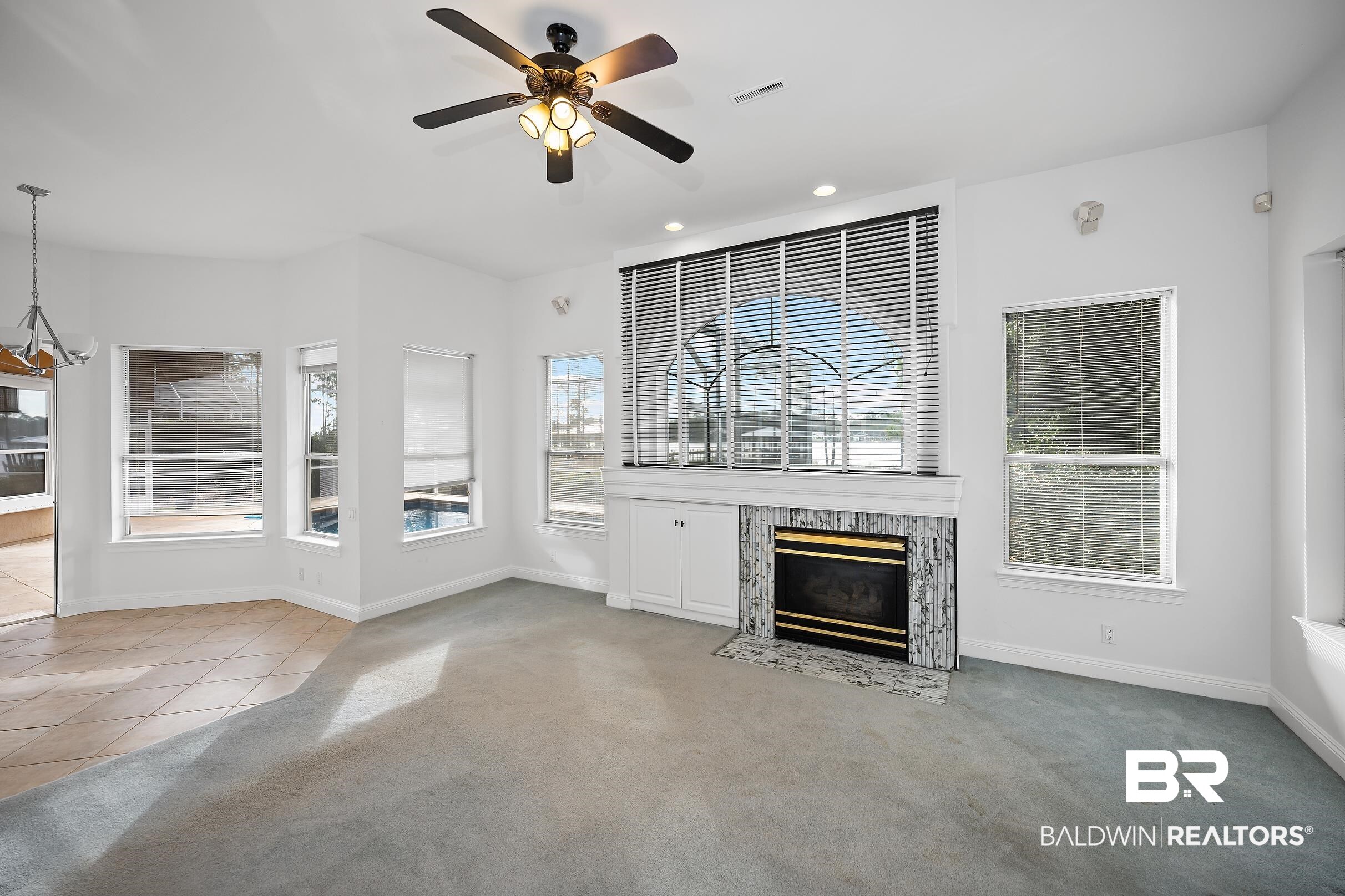 8591 Bay Harbor Road Elberta, AL 36530 - Photo 14 of 56 Unfurnished living room featuring light colored carpet, a high end fireplace, plenty of natural light, recessed lighting, and a ceiling fan