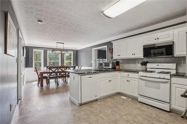 a kitchen with appliances a sink and chairs
