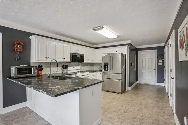 a kitchen with stainless steel appliances granite countertop a refrigerator stove microwave and sink