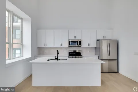 a kitchen with stainless steel appliances a refrigerator sink and white cabinets