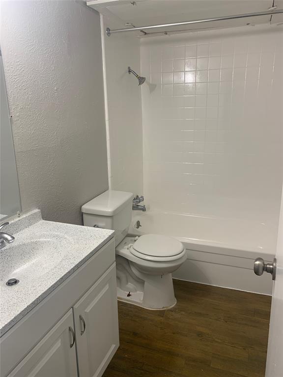 4606 Monarch Street, Unit 215 Dallas, TX 75204 - Photo 9 of 14 Full bath with a textured wall, vanity, dark wood-style flooring, and washtub / shower combination