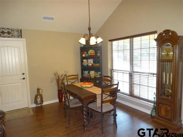 a dining room with furniture wooden floor a potted plant and a chandelier