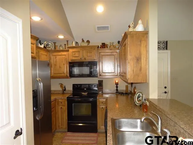 a kitchen with stainless steel appliances granite countertop a sink a stove and a refrigerator