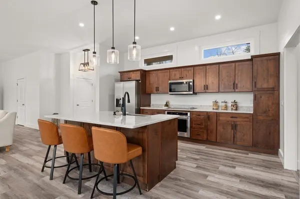 a kitchen with stainless steel appliances granite countertop a sink a stove a refrigerator and a dining table with wooden floor