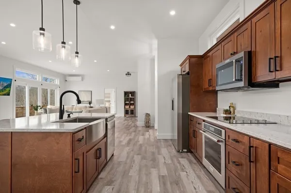 a kitchen with stainless steel appliances granite countertop a sink a stove and a wooden floors