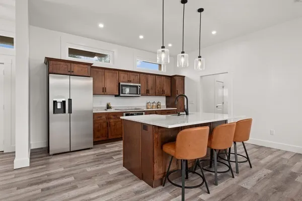 a kitchen with stainless steel appliances granite countertop a sink window and chairs