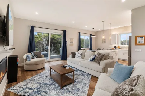 a living room with stainless steel appliances furniture and a kitchen view
