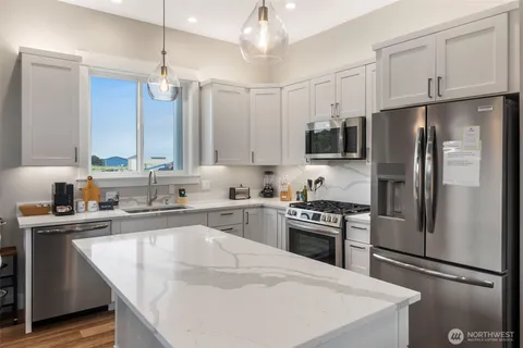 a kitchen with stainless steel appliances a sink a stove a microwave a center island and cabinets