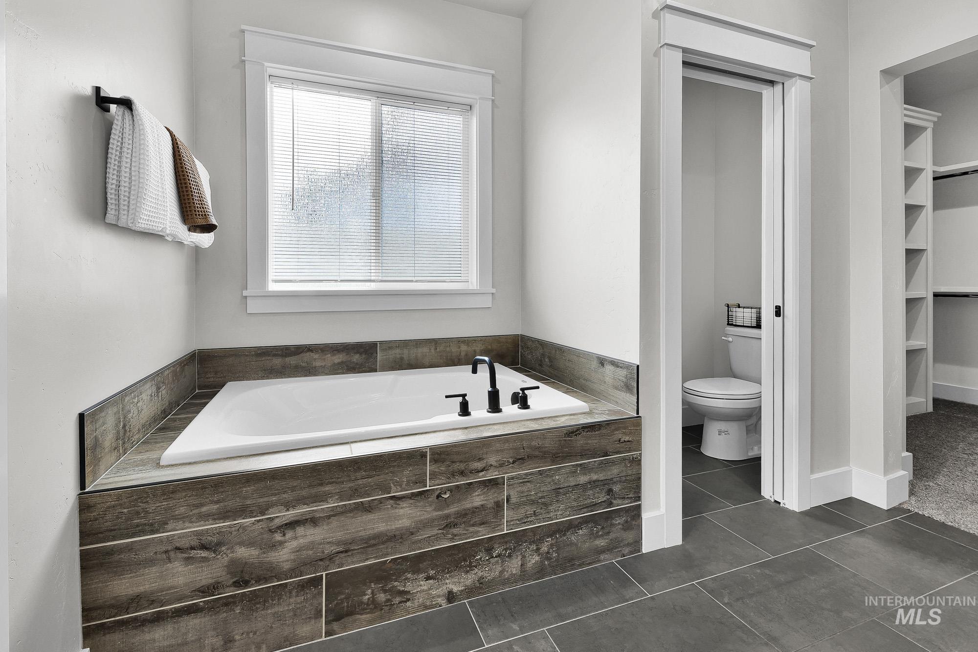 5676 East Zaffre Ridge Street Boise, ID 83716 - Photo 29 of 50 Built-in soaking tub with wood-look tile surround and matte black fixtures
