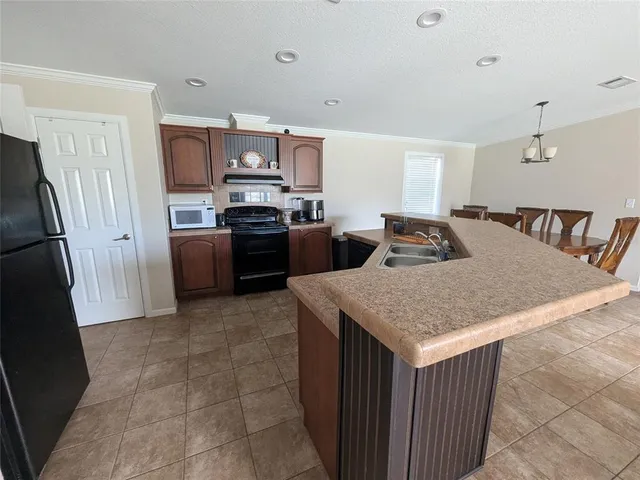 a kitchen with stainless steel appliances granite countertop a table chairs sink refrigerator and cabinets