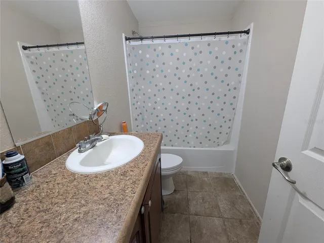 a bathroom with a granite countertop sink a toilet and shower
