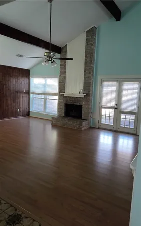 a view of an empty room with window and wooden floor