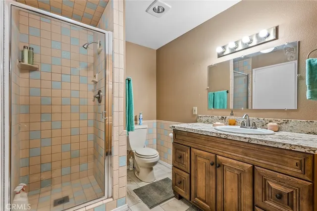 a bathroom with a granite countertop toilet sink and mirror