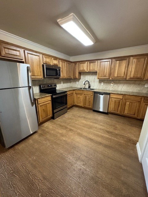 101 Calvin Smith Ln., Unit B Jarrell, TX 76537 - Photo 8 of 33 Kitchen featuring ornamental molding, stainless steel appliances, wood-like finished floors, wood finish cabinets, and tasteful backsplash!