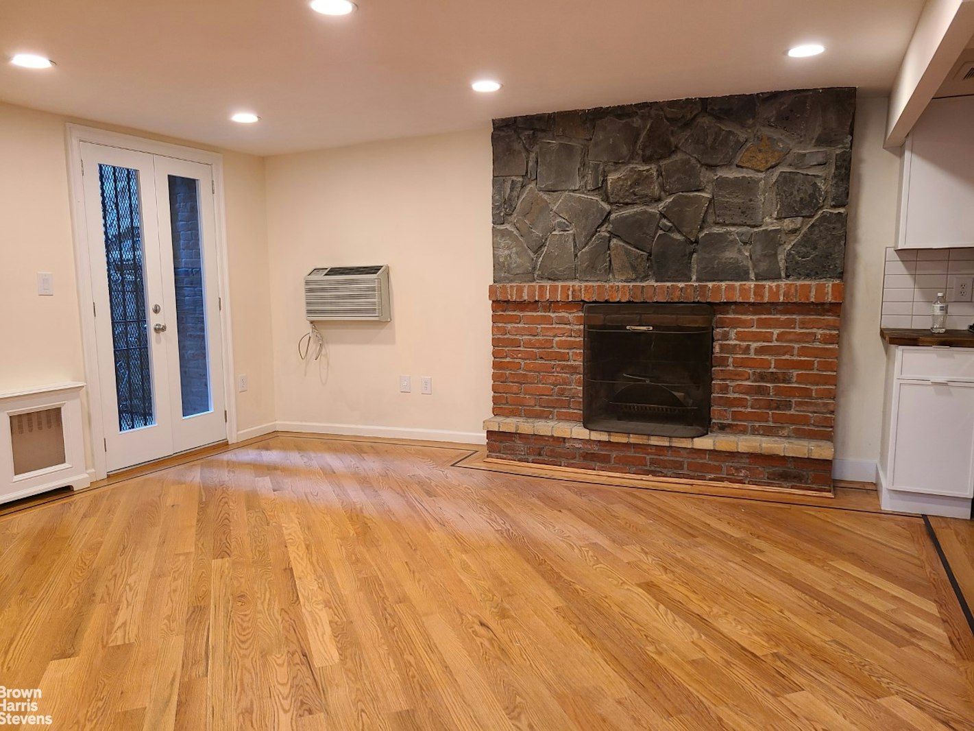 a view of an empty room with wooden floor and a fireplace