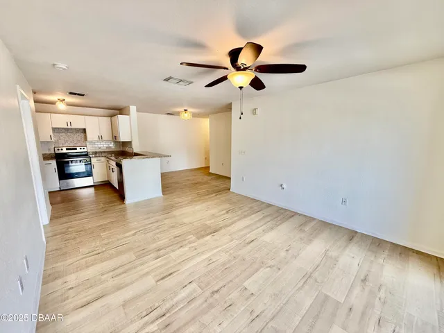 a view of a kitchen with wooden floor a sink a refrigerator and window