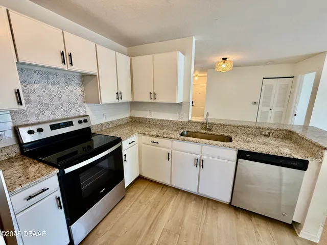 a kitchen with granite countertop a stove sink and cabinets