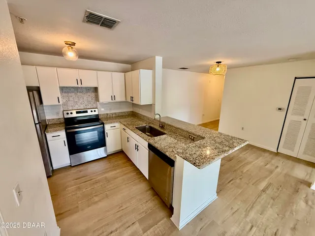 a kitchen with granite countertop a sink stove and refrigerator