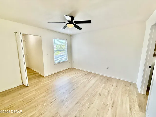 a view of empty room with wooden floor and fan