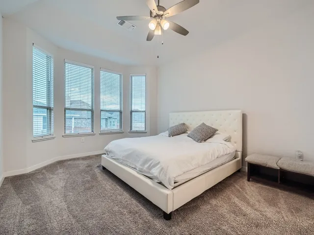 a bed sitting in a spacious bedroom next to a window