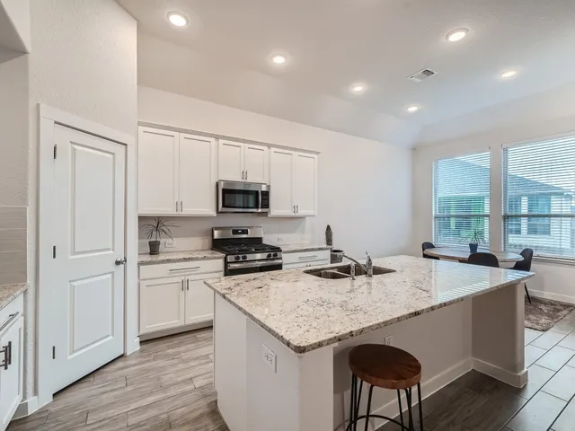 a kitchen with stainless steel appliances granite countertop a kitchen island hardwood floor sink stove and granite counter top