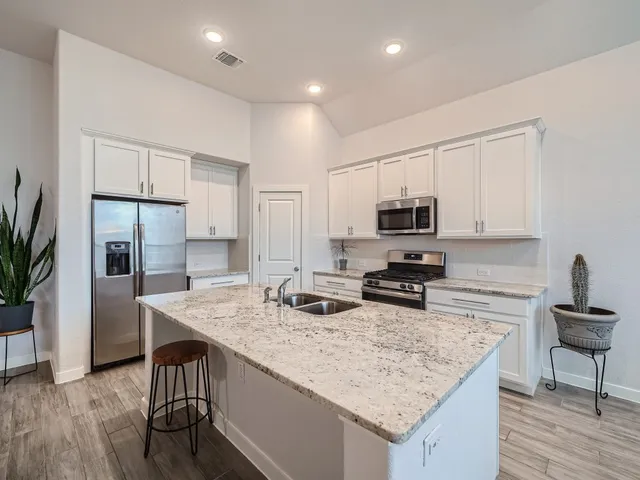 a kitchen with granite countertop a stove refrigerator and microwave