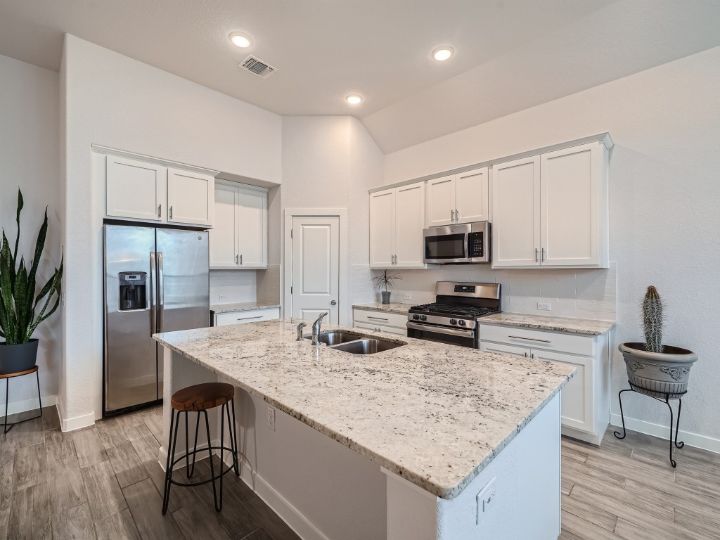 11400 American Mustang Loop Manor, TX 78653 - Photo 6 of 24 a kitchen with granite countertop a stove refrigerator and microwave