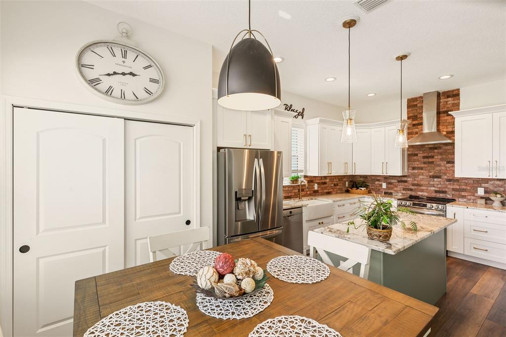 6206 Five Acre Road Plant City, FL 33565 - Photo 12 of 33 a kitchen with stainless steel appliances granite countertop a stove a refrigerator a sink a dining table and chairs with the wooden floor