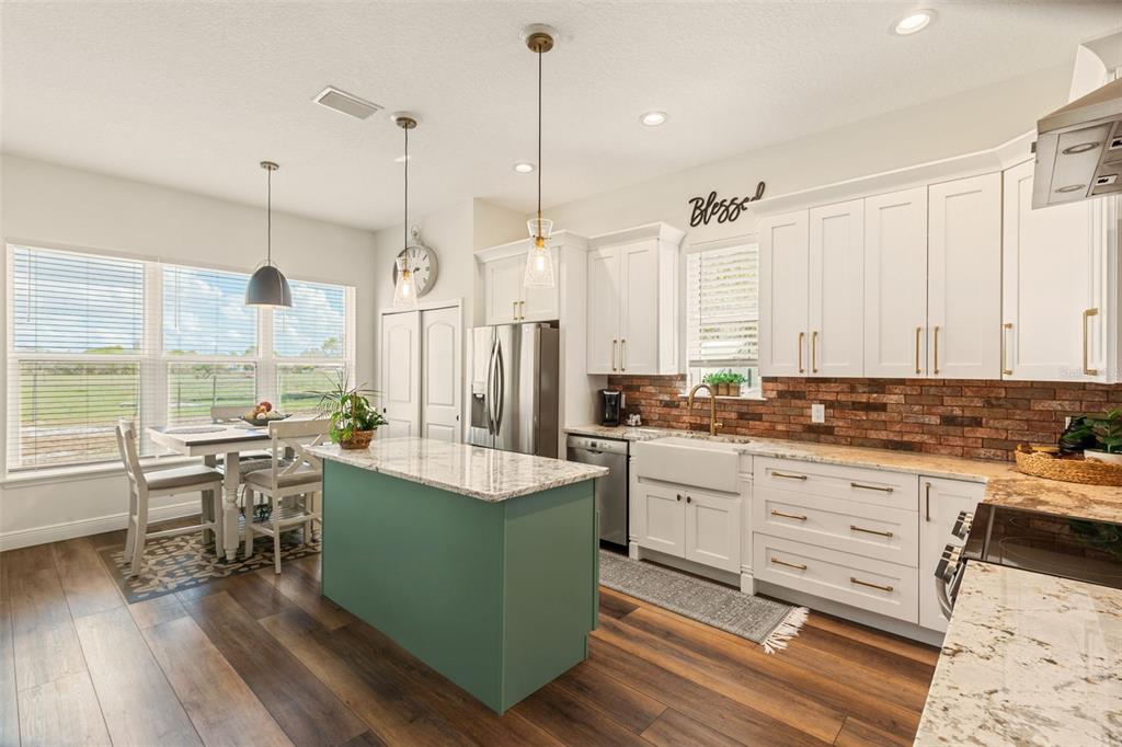 6206 Five Acre Road Plant City, FL 33565 - Photo 10 of 33 a large kitchen with kitchen island a stove a sink dishwasher a dining table and chairs with wooden floor