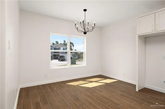 an empty room with wooden floor chandelier and windows