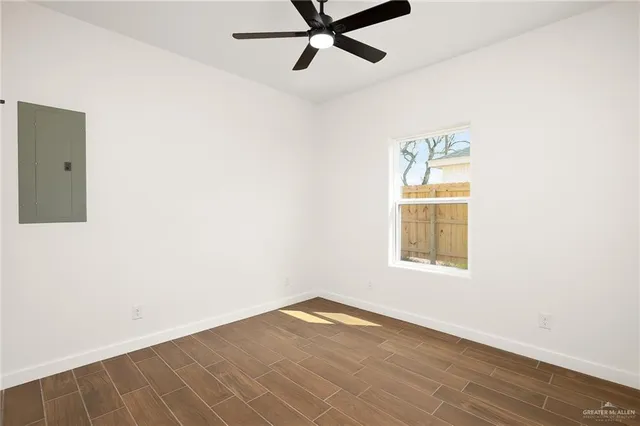 a view of empty room with wooden floor and fan