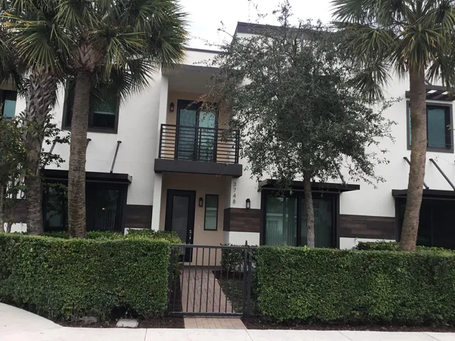 front view of house with a yard and palm trees