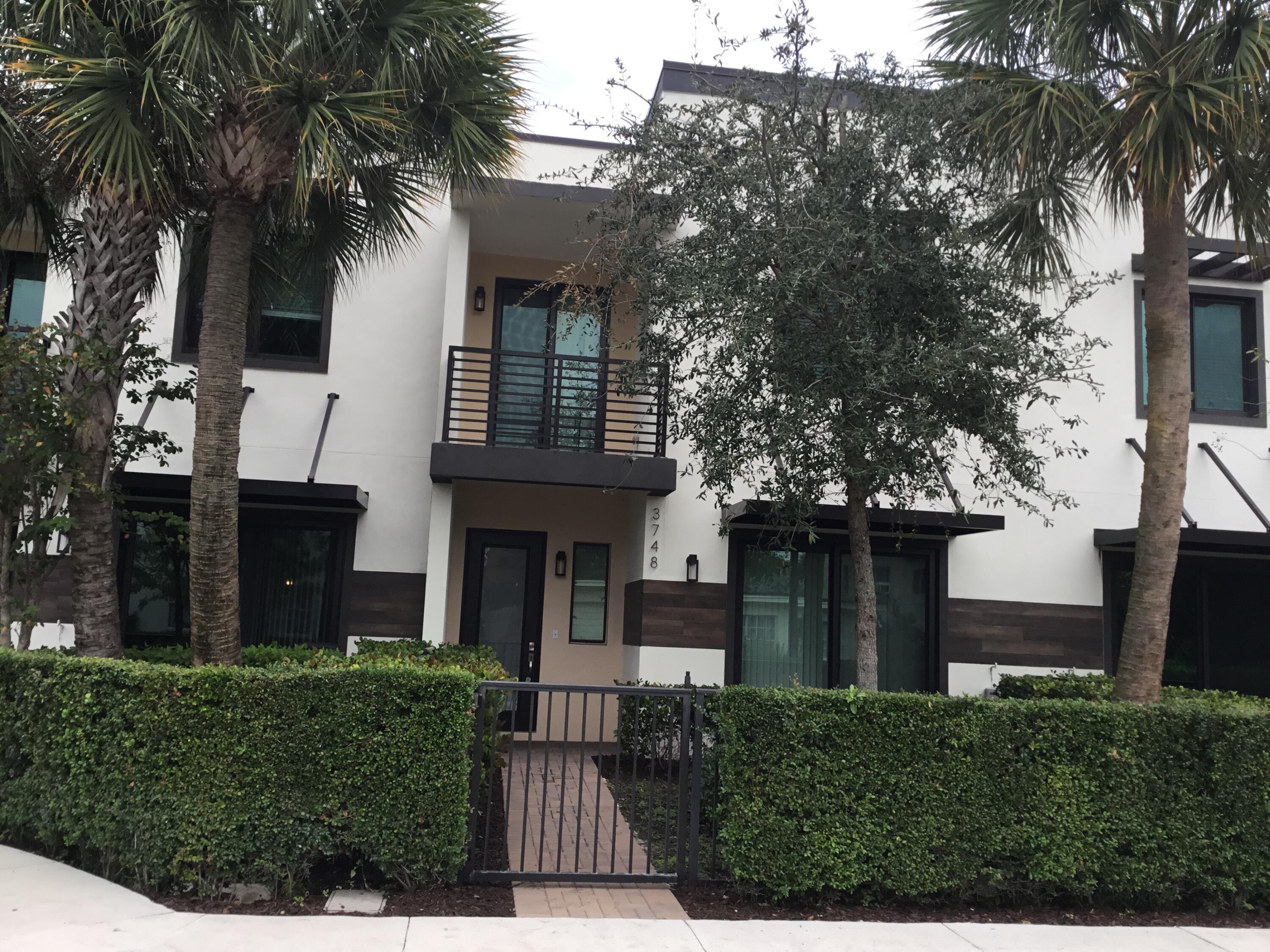 front view of house with a yard and palm trees