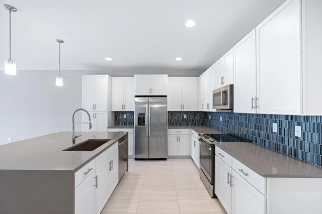 a kitchen with kitchen island granite countertop a sink and refrigerator