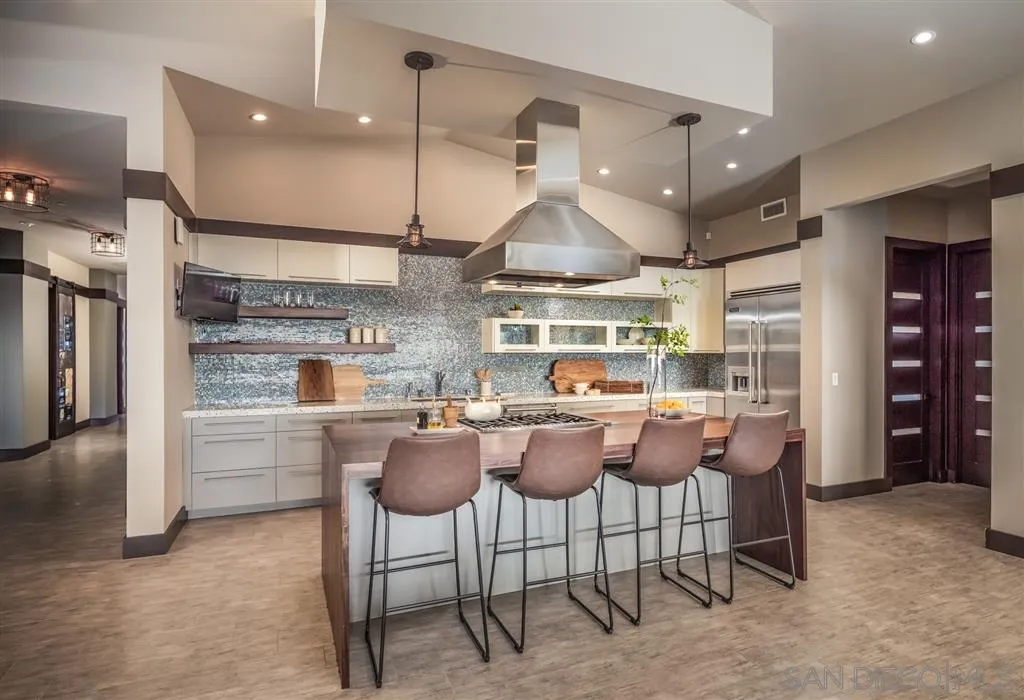 5630 Soledad Road La Jolla, CA 92037 - Photo 10 of 25 a kitchen with stainless steel appliances kitchen island granite countertop a table chairs sink and cabinets