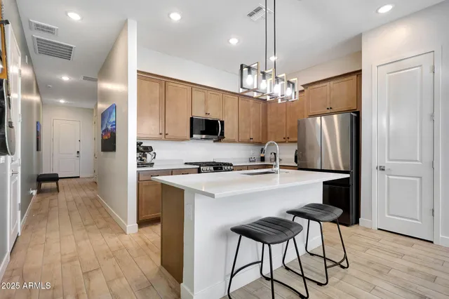 a kitchen with kitchen island granite countertop a refrigerator a stove a oven and white cabinets with wooden floor