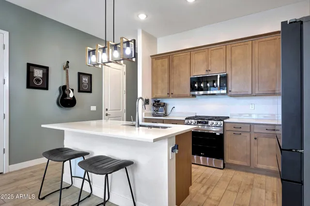 a kitchen with stainless steel appliances granite countertop a stove top oven a sink dishwasher and a refrigerator with wooden floor