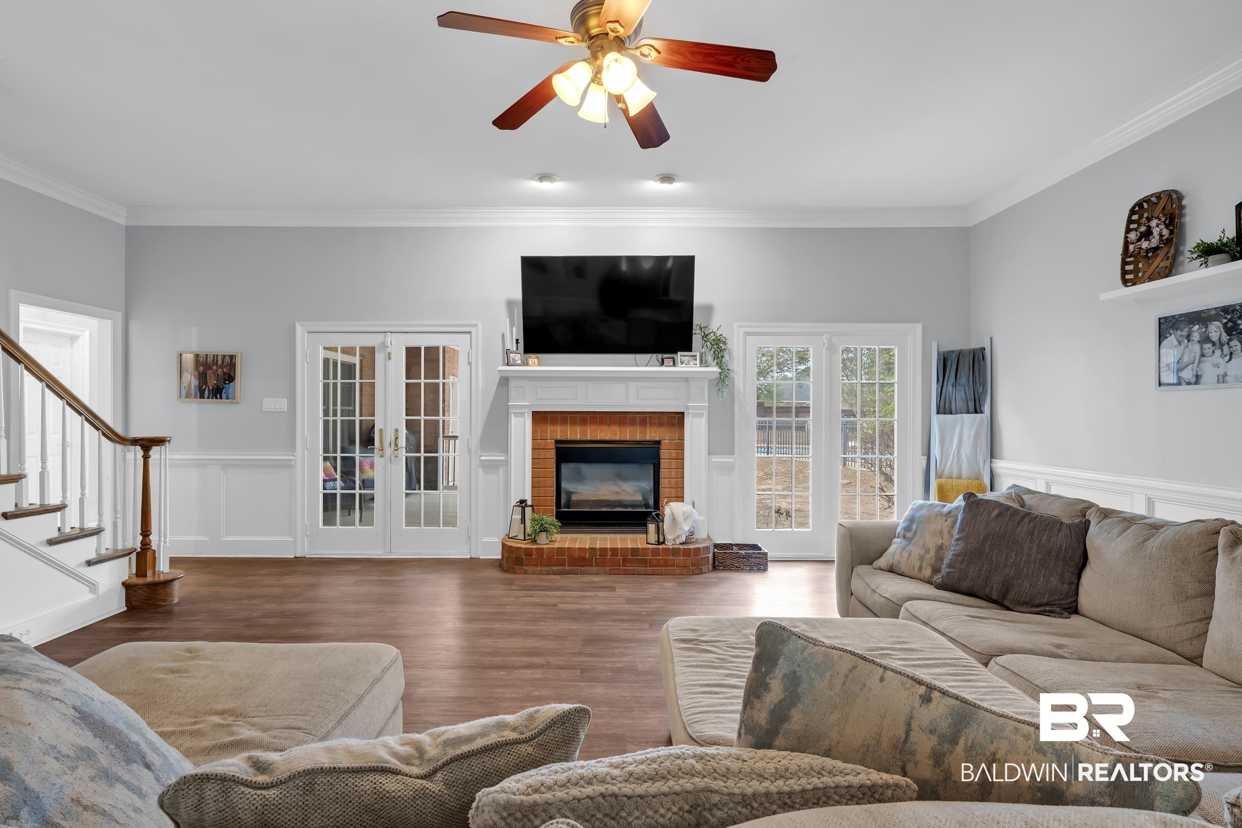 2858 Postoak Circle Mobile, AL 36693 - Photo 15 of 32 Living room featuring a decorative wall, a wainscoted wall, crown molding, wood finished floors, and stairs