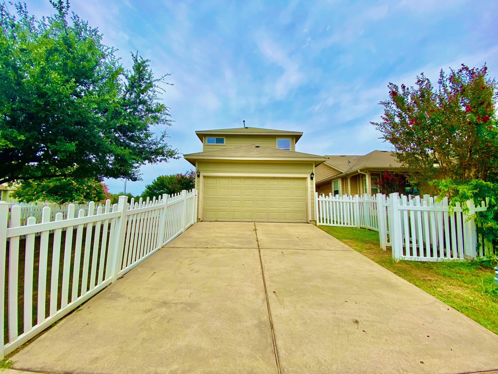 1000 Berry Bend Path Round Rock, TX 78664 - Photo 19 of 20 A welcoming front exterior features a paved driveway leading to an integrated garage, bordered by a classic picket fence and mature landscaping.